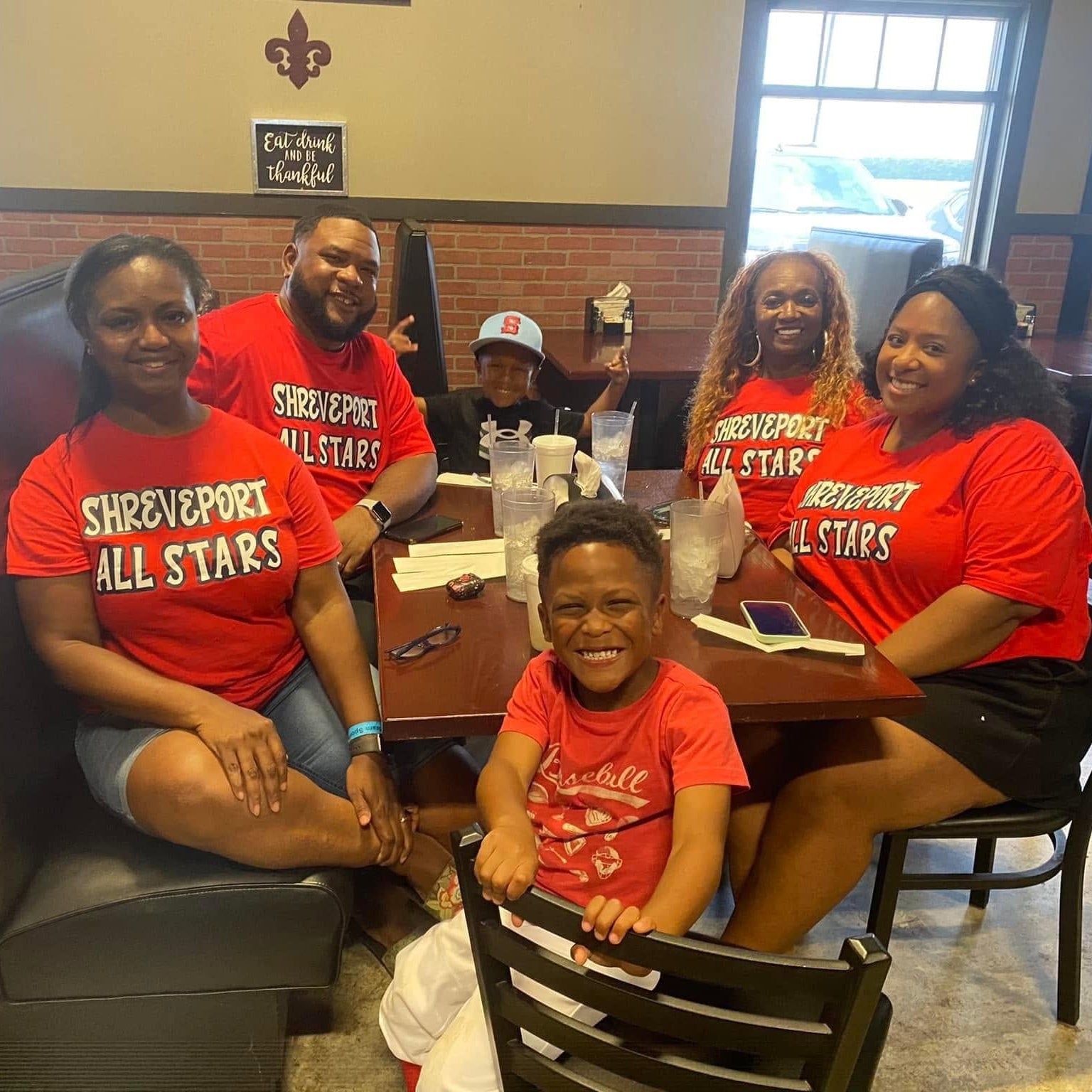 Family wearing 'Shreveport All Stars' shirts in a restaurant setting